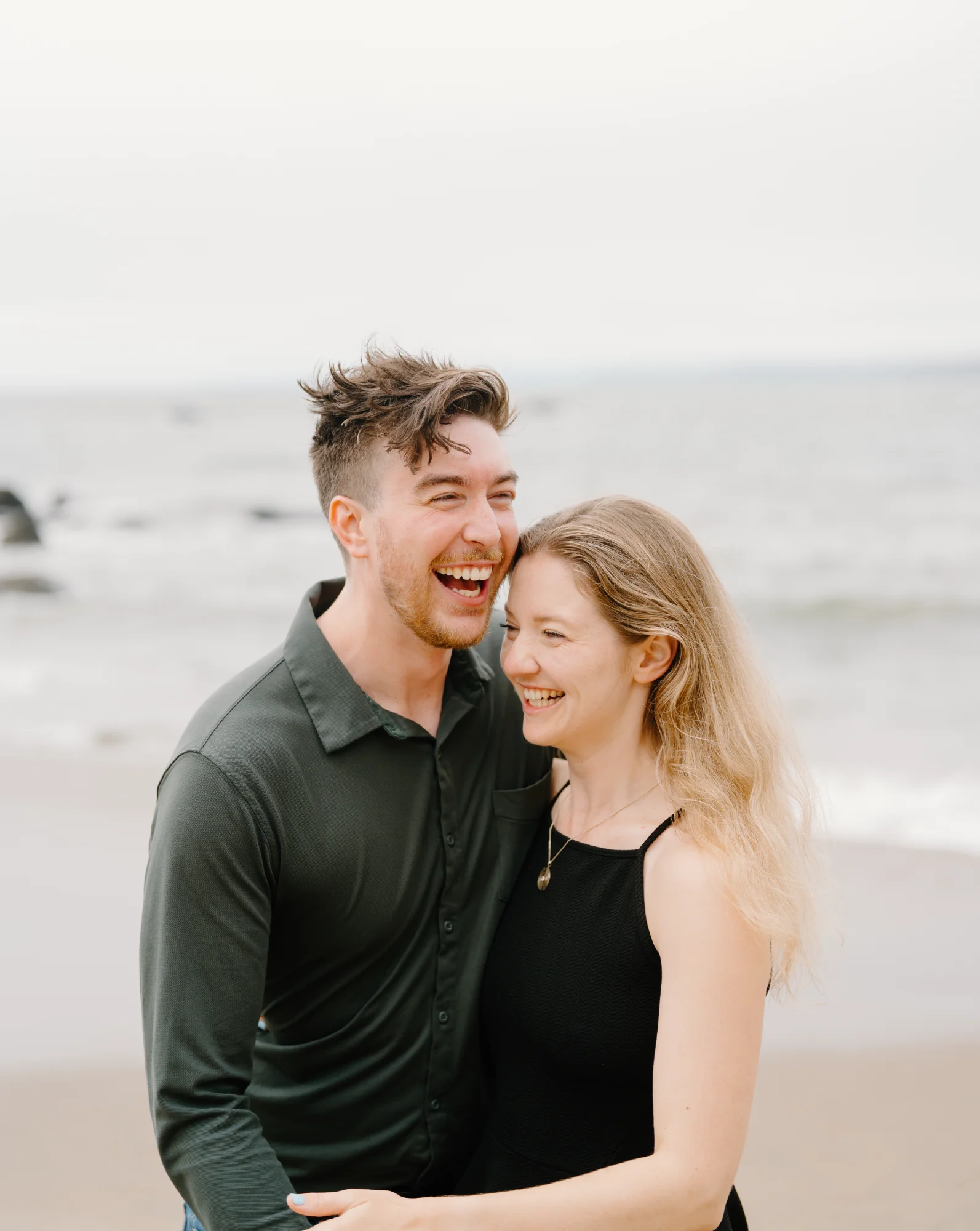Matt and Amélie laughing together by the ocean